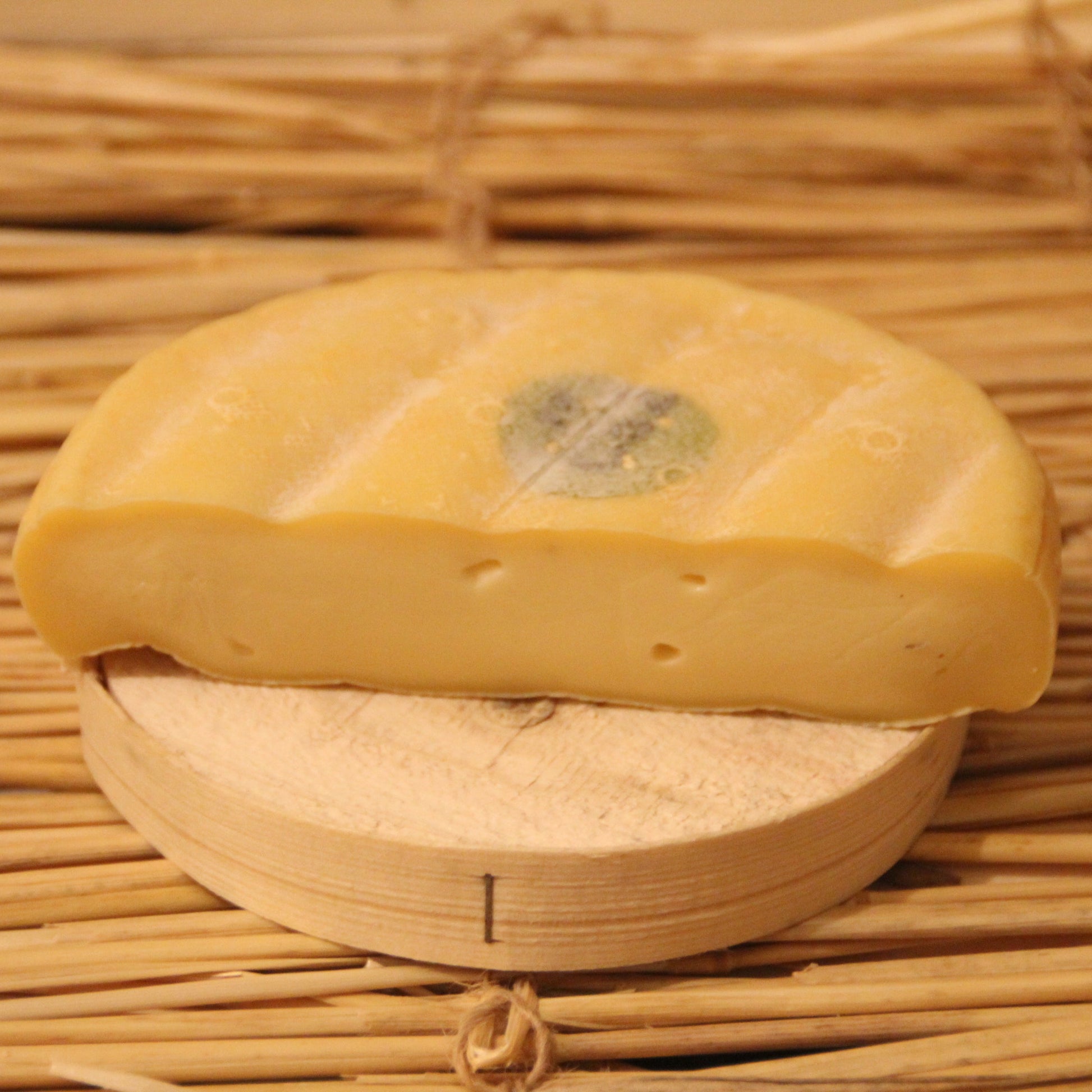 Half-cut piece of cheese on a woven mat